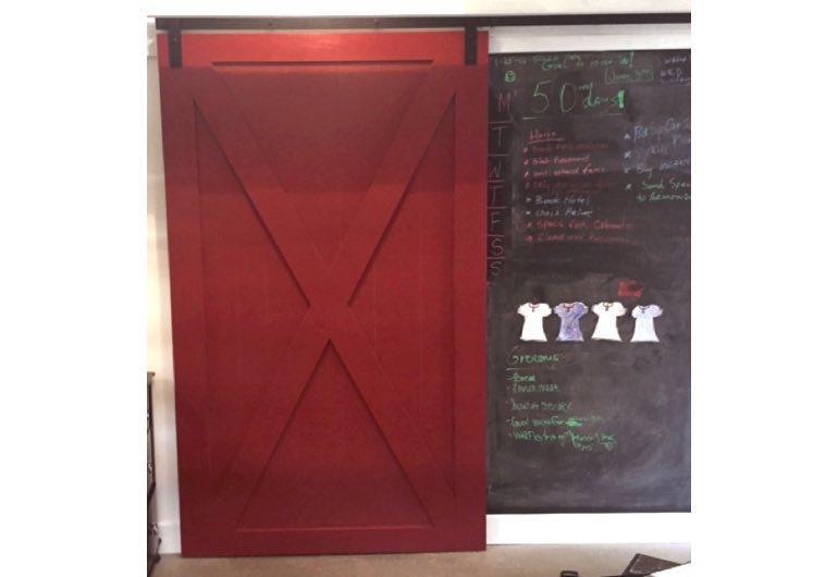 Red barn door with black hardware next to chalkboard 